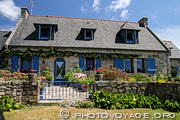 Jolie maison bretonne typique aux volets bleus dans un village de la presqu'île de Crozon. Les jardins sont toujours très fleuris.