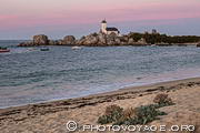 Ciel rose, chou marin sur la plage et phare de Ponstuval &eacute;rig&eacute; &agrave; la pointe de Beg-Pol dans la commune de Brignogan-Plage.