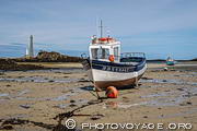 Bateau &eacute;chou&eacute; &agrave; mar&eacute;e basse &agrave; la pointe du Kastell-Ac'h avec le phare de l'&Icirc;le Vierge en arri&egrave;re plan.