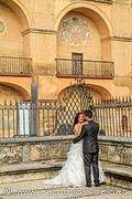 Couple de mariés posant pour leurs photos de mariage devant la jolie grille 
du square de la Plaza del Triunfo avec le mur à arcades de l'ancienne mosquée 
en toile de fond.