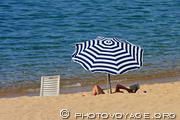 lecture sur la plage sous un parasol rayé au bord de l'eau