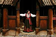 Femme en costume traditionnel devant la stavkirke de Gol