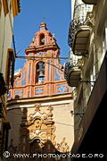 Coup d'oeil sur le clocher et le portail aux sculptures en terre cuite de la Capilla de San José vus depuis la rue Sierpes