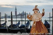 Costumée posant devant les gondoles et l'île de San Giorgio lors 
du carnaval de Venise.