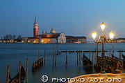 Vue typique de Venise à l'heure bleue : une gondole, un réverbère 
allumé, un quai d'embarquement, les eaux du bassin de San Marco et l'église 
San Giorgio joliment illuminée de nuit.