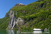 Vue générale de la cascade des 7 soeurs plongeant dans le Geirangerfjord avec un ferry donnant l'échelle de grandeur.