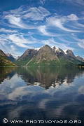 Reflet des montagnes de Hjelle dans le lac Oppstrynsvatnet sous un ciel chargé de cirrus floccus virga.